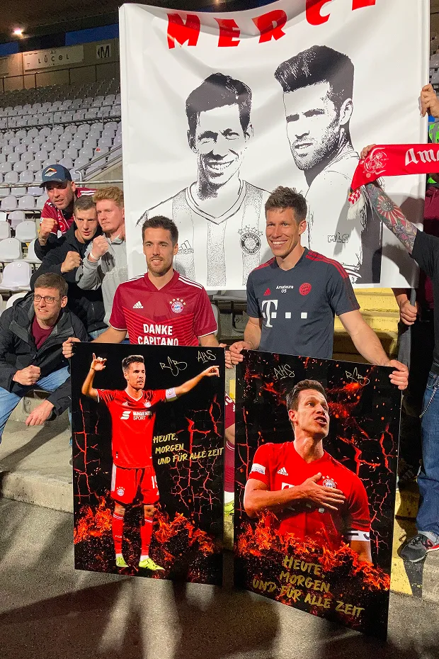 FC-Bayern Spieler halten zwei große Platten, auf denen ihre Gesichter abgedruckt sind.