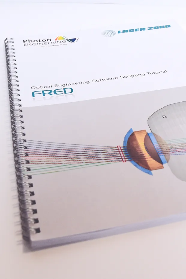 Ein Spiralbuch mit dem Titel "FRED" und einer grafischen Darstellung von Lichtstrahlen durch eine Linse.