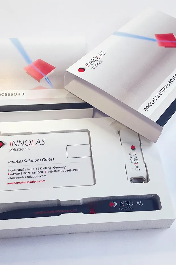 Verpackung mit einem Stift und einer Karte von INNOLAS Solutions, auf einem hellen Hintergrund.