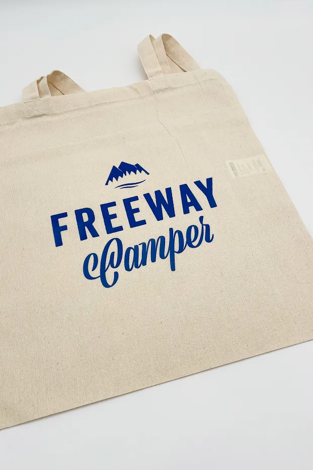 Beige Baumwolltasche mit blauer Aufschrift "FREEWAY Camper" und einem Bergsymbol darüber.