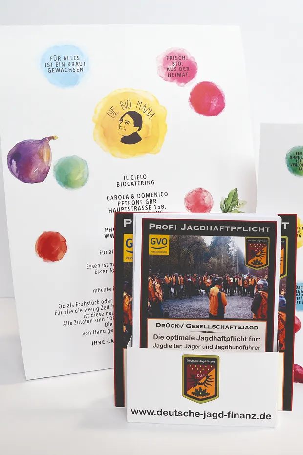 Ein Flyer mit bunten Illustrationen und mehreren Broschüren über Jagdpflichten im Vordergrund.