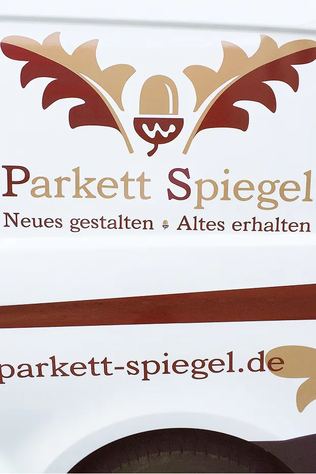 Logo von Parkett Spiegel mit Schriftzug und dekorativen Elementen in Braun- und Beigetönen auf einem Kastenwagen.